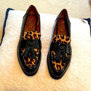 Black slip on elevator shoes with textured animal print and tassels.